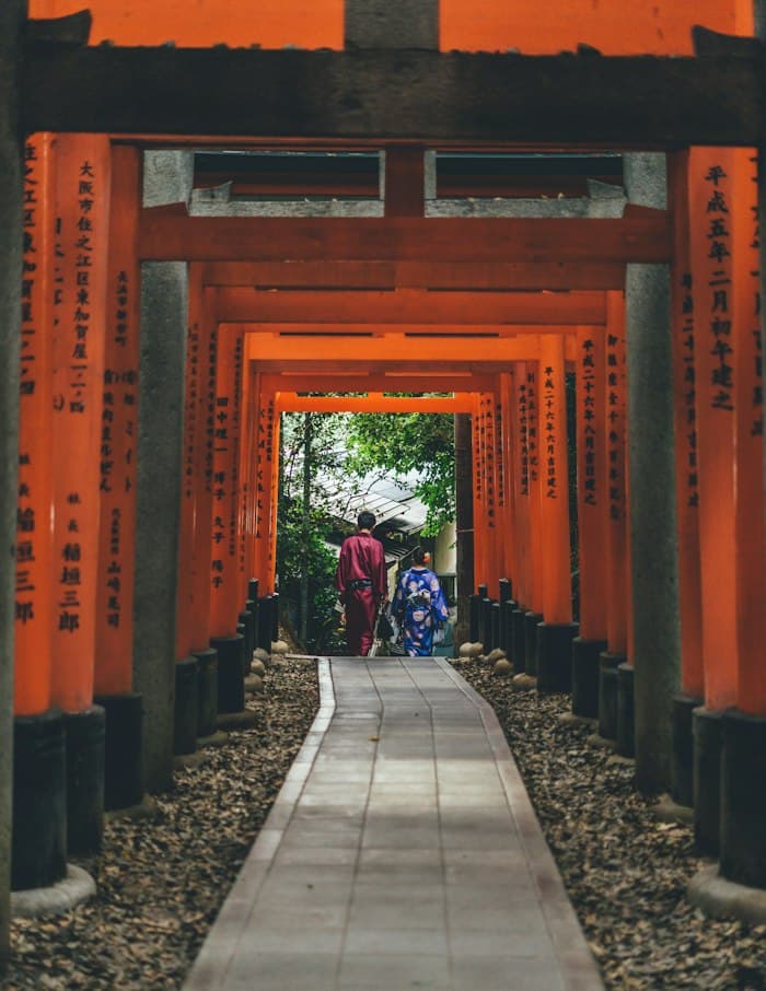 朱色の鳥居が連なる参道を歩く二人の後ろ姿