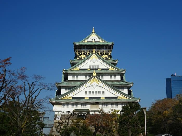 青空を背景に立つ、緑の屋根と白い壁の天守