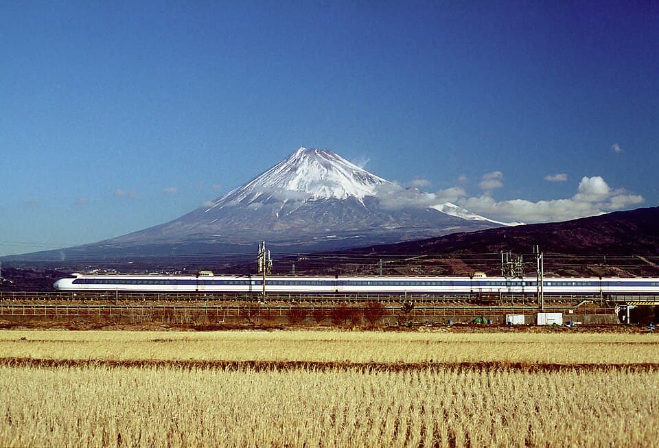 雪を頂く富士山と、その手前を走る新幹線0系。1999年撮影